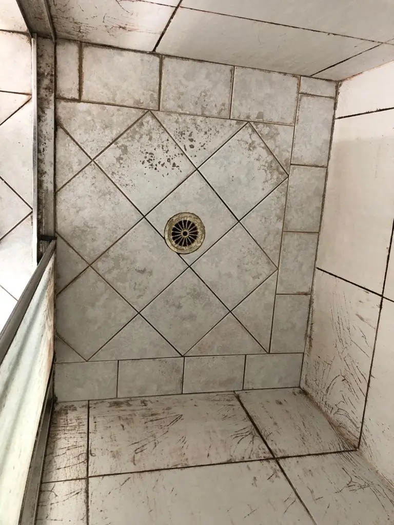 Before: grey shower base with dark stained grout.